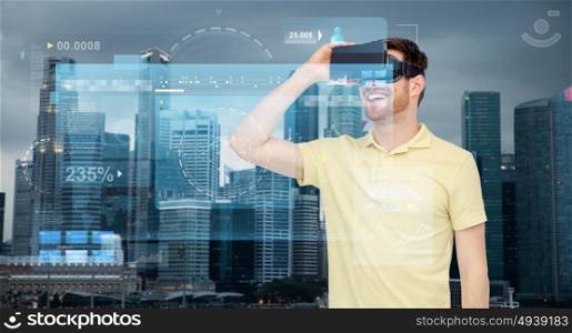 technology, augmented reality, entertainment and people concept - happy young man with virtual headset or 3d glasses over singapore city skyscrapers background and screens projection. happy man in virtual reality headset or 3d glasses