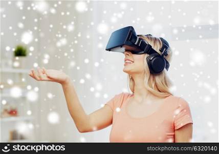 technology, augmented reality, entertainment and people concept - happy young woman in virtual headset or 3d glasses and headphones playing game at home and holding something invisible. woman in virtual reality headset or 3d glasses