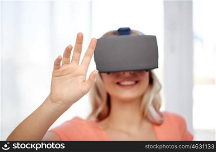 technology, augmented reality, entertainment and people concept - happy young woman with virtual reality headset or 3d glasses touching something invisible