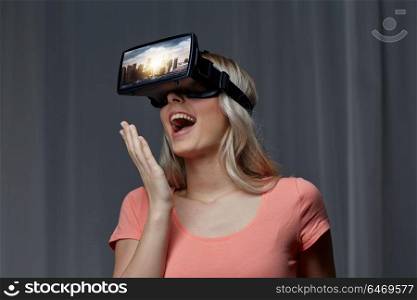 technology, augmented reality, entertainment and people concept - happy young woman with virtual headset or 3d glasses playing video game with singapore city on screen in dark room. woman in virtual reality headset or 3d glasses