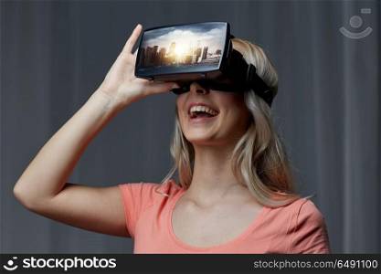 technology, augmented reality, entertainment and people concept - happy young woman with virtual headset or 3d glasses playing video game with singapore city on screen in dark room. woman in virtual reality headset or 3d glasses. woman in virtual reality headset or 3d glasses