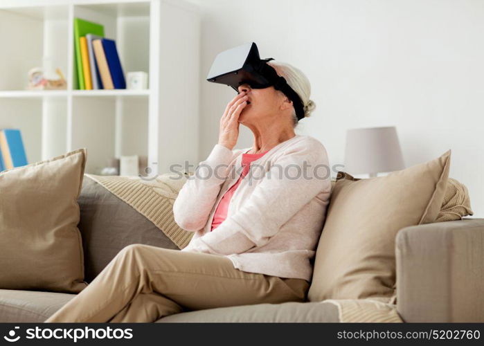 technology, augmented reality, entertainment and people concept - senior woman with virtual headset or 3d glasses playing videogame at home. old woman in virtual reality headset or 3d glasses