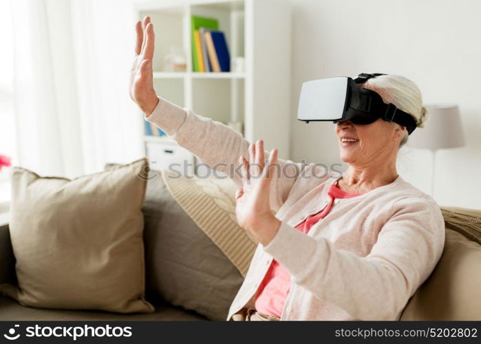 technology, augmented reality, entertainment and people concept - senior woman with virtual headset or 3d glasses playing videogame at home. old woman in virtual reality headset or 3d glasses