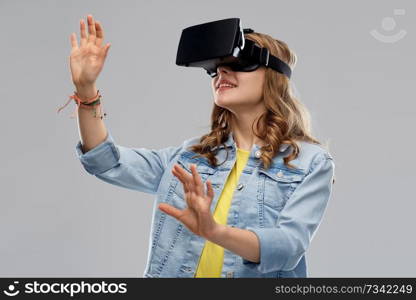 technology, augmented reality, entertainment and people concept - teenage girl in virtual headset or vr glasses over grey background. teen girl in virtual reality headset or vr glasses