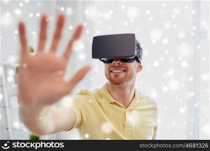 technology, augmented reality, gaming, entertainment and people concept - happy young man with virtual headset or 3d glasses playing video game over snow