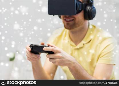 technology, augmented reality, gaming, entertainment and people concept - man in headphones with virtual headset 3d glasses and headphones playing video game with controller gamepad at home over snow