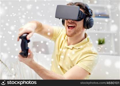technology, augmented reality, gaming, entertainment and people concept - young man in headphones with virtual headset or 3d glasses with controller gamepad playing racing video game at home over snow