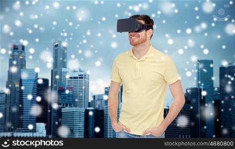 technology, augmented reality, winter, christmas and people concept - happy young man with virtual headset or 3d glasses over snow and singapore city skyscrapers background