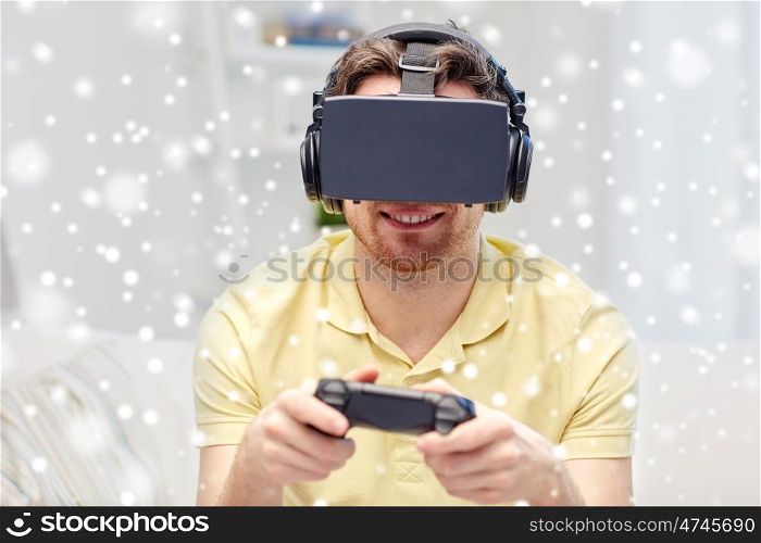 technology, augmented reality, winter, christmas and people concept - happy young man with virtual headset or 3d glasses playing video game with controller gamepad at home over snow