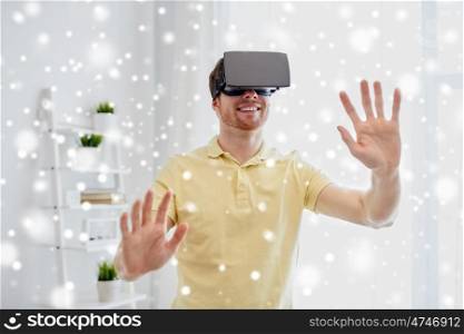 technology, augmented reality, winter, christmas and people concept - happy young man with virtual headset or 3d glasses playing video game at home over snow