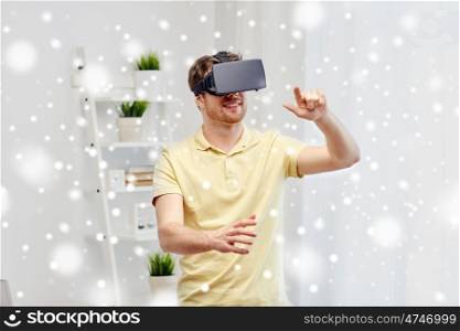 technology, augmented reality, winter, christmas and people concept - happy young man with virtual headset or 3d glasses playing video game over snow