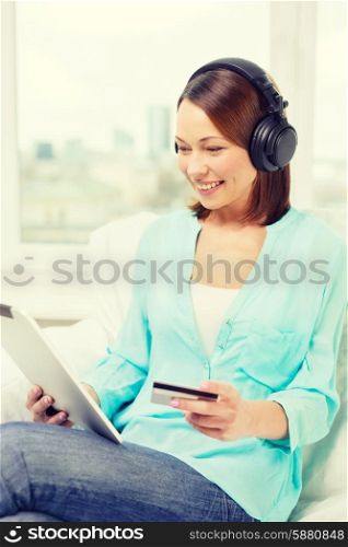 technology, banking, money, internet and home concept - smiling woman with tablet pc computer, headphones and credit card at home