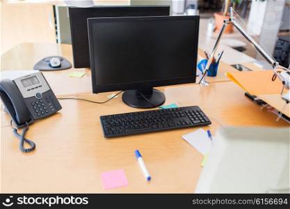 technology, business and advertisement concept - computers with blank black screen on office table