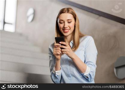 technology, business and corporate concept - happy smiling woman or student with smartphone at office stairs. woman or student with smartphone at office stairs