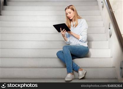 technology, business and corporate concept - woman or student with tablet pc computer sitting on stairs. woman or student with tablet pc sitting on stairs