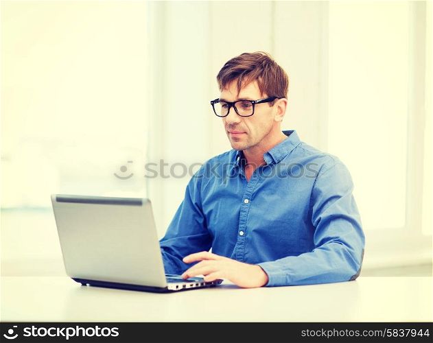technology, business and lifestyle concept - man in eyeglasses working with laptop at home