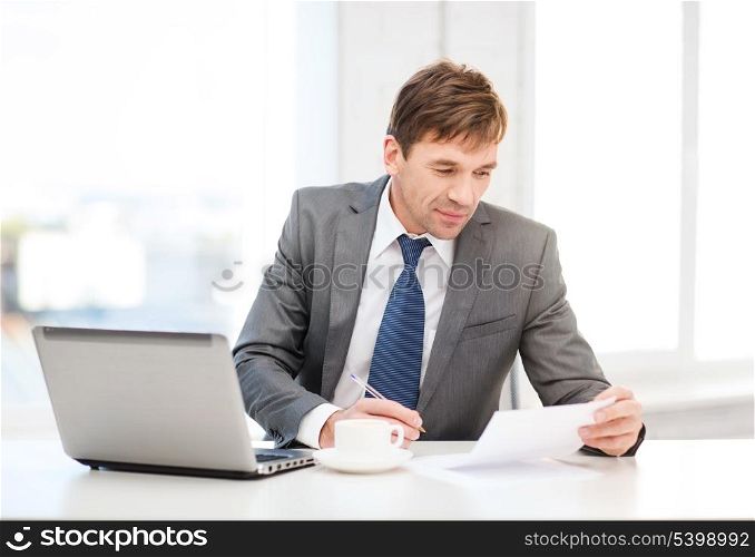 technology, business and office concept - handsome businessman working with laptop computer and documents