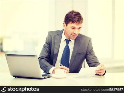 technology, business and office concept - handsome businessman working with laptop computer and documents