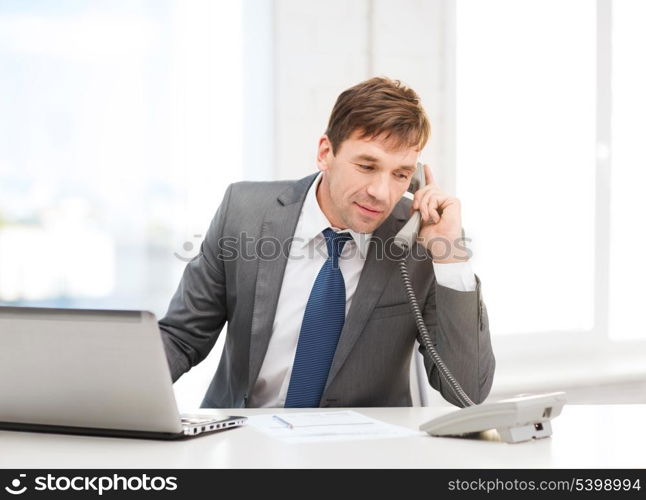 technology, business and office concept - handsome businessman working with laptop computer, phone and documents