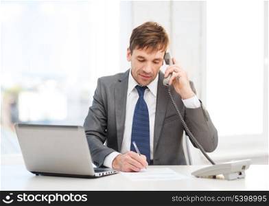 technology, business and office concept - handsome businessman working with laptop computer, phone and documents