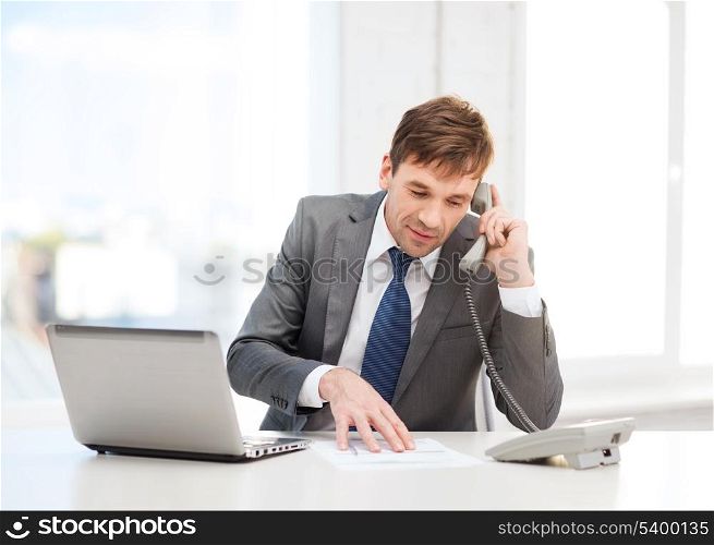 technology, business and office concept - handsome businessman working with laptop computer, phone and documents