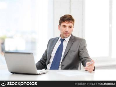 technology, business and office concept - puzzled businessman working with laptop computer and documents