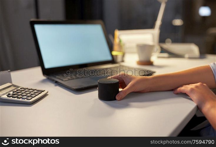 technology, business and people concept - hand using smart speaker at night office. hand using smart speaker at night office