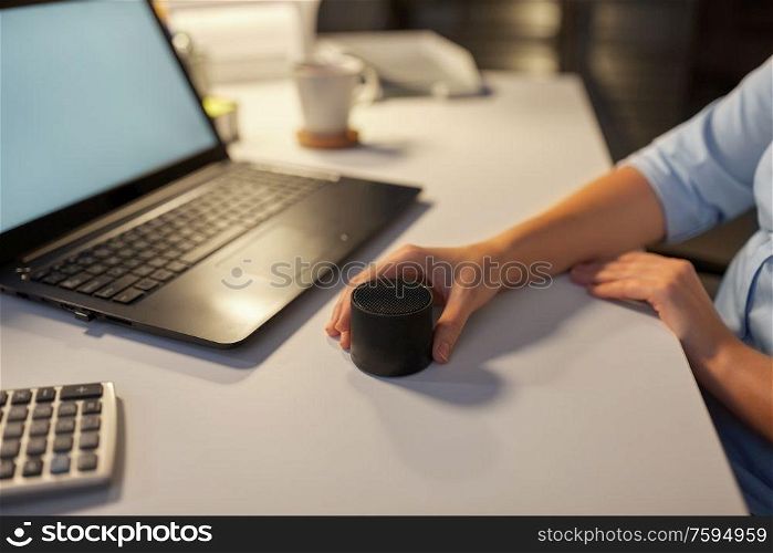 technology, business and people concept - hand using smart speaker at night office. hand using smart speaker at night office