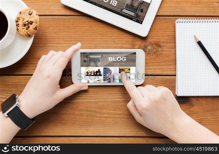 technology, business, communication, people and advertisement concept - close up of woman with blank smartphone screen and coffee cup on wooden table
