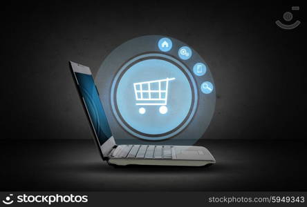 technology, business, e-commerce and sale concept - open laptop computer with shopping trolley icon projection over dark gray background