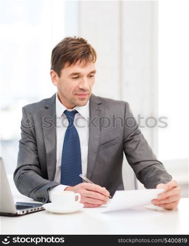 technology, business, education and office concept - handsome businessman working with laptop computer and documents