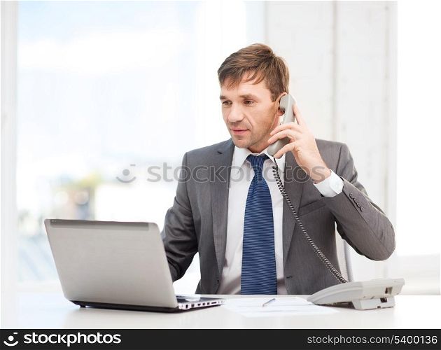 technology, business, education and office concept - handsome businessman working with laptop computer, phone and documents