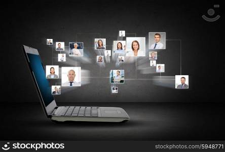 technology, business, internet and communication concept - open laptop computer with internet contacts icons projection over dark gray background