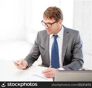 technology, business, internet and office concept - handsome businessman working with laptop computer and smartphone
