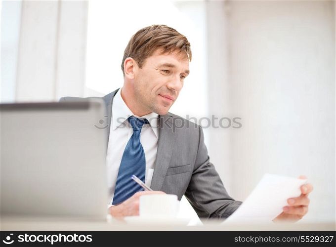 technology, business, internet and office concept - handsome businessman working with laptop computer, coffee and documents