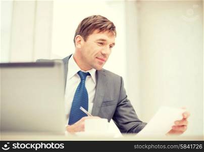 technology, business, internet and office concept - handsome businessman working with laptop computer, coffee and documents