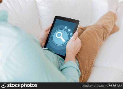 technology, business, leisure and people concept - close up of man holding tablet pc computer with magnifying glass icon on screen and sitting on sofa at home