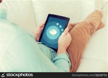 technology, business, leisure and people concept - close up of man holding tablet pc computer with text bubble icon on screen sitting on sofa at home