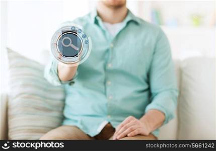 technology, business, leisure and people concept - close up of man showing tablet pc computer screen with magnifying glass icon on it and sitting on sofa at home