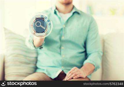 technology, business, leisure and people concept - close up of man showing tablet pc computer screen with magnifying glass icon on it and sitting on sofa at home