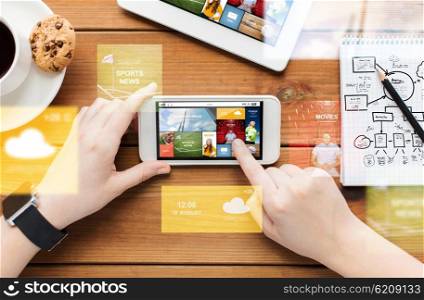 technology, business, people and media concept - close up of woman with internet news on smartphone screen and coffee cup on wooden table
