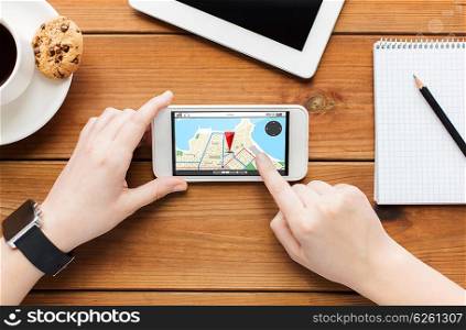 technology, business, people and navigation concept - close up of woman with gps navigator map on smartphone screen and coffee cup on wooden table