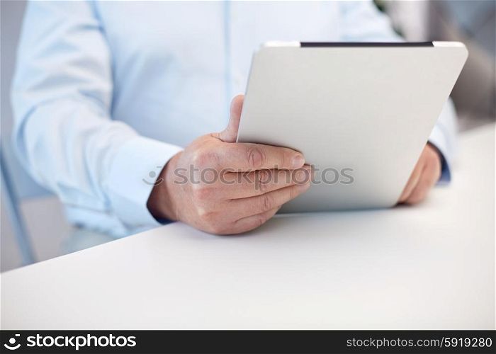 technology, business, retirement, people and leisure concept - close up of senior man hands with tablet pc computer at table in office
