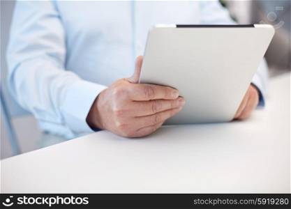 technology, business, retirement, people and leisure concept - close up of senior man hands with tablet pc computer at table in office