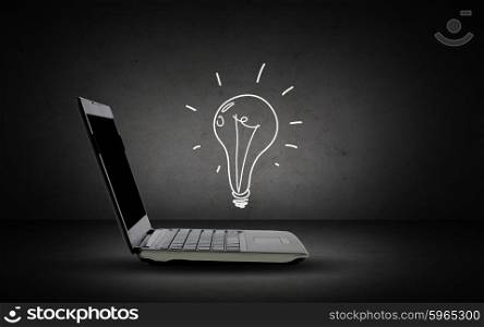 technology, business, start up and idea concept - open laptop computer with lighting bulb doodle over dark gray background