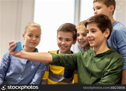 technology, children and people concept - group of happy kids or friends taking selfie with smartphone