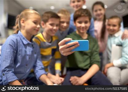 technology, children and people concept - group of happy kids or friends taking selfie with smartphone. group of happy kids taking selfie with smartphone