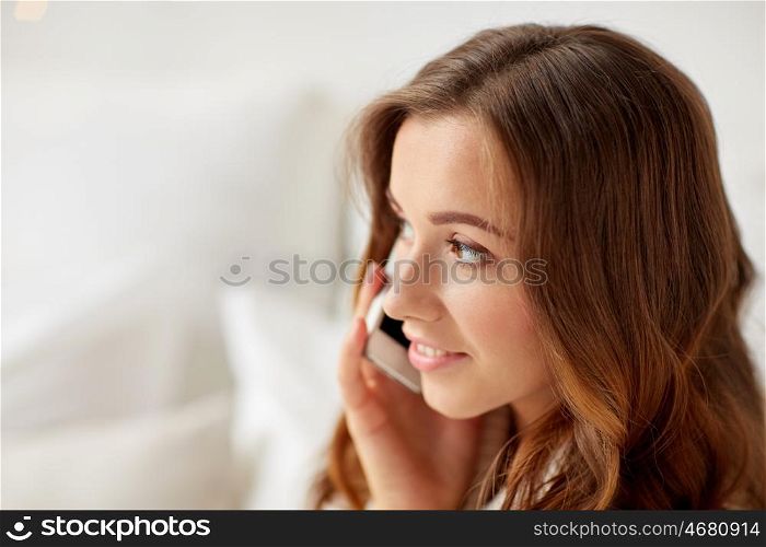technology, christmas, communication and people concept - happy young woman calling on smartphone at home
