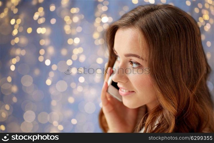 technology, christmas, communication and people concept - happy young woman calling on smartphone at home. happy young woman calling on smartphone at home