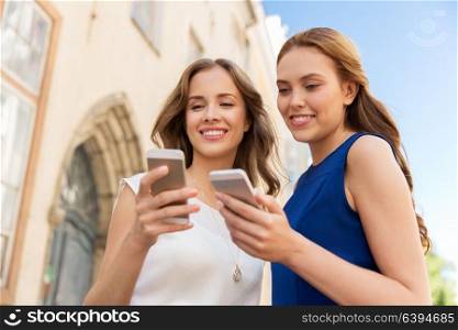 technology, cloud computing and people concept - happy young women with martphones on city street. happy women with smartphones on city street